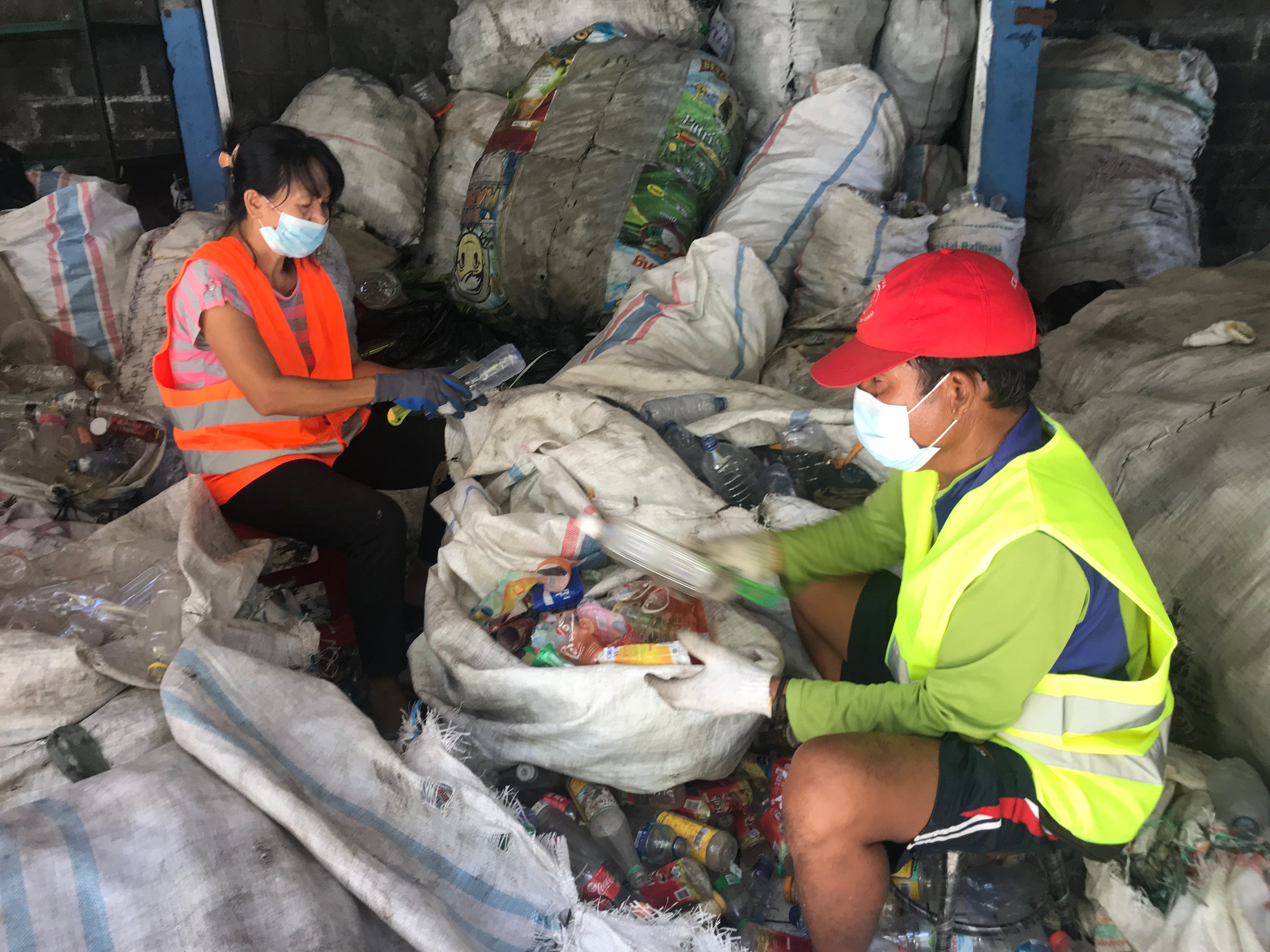 Two workers sorting through recyclables in a recycling facility.